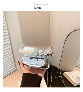 Detail of silver metallic mini bag with large pearl and heart-shaped handle strap