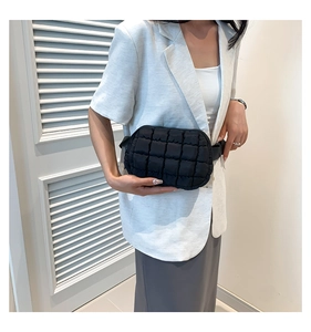 Close-up of black quilted nylon crossbody bag on a model wearing an off-white blazer