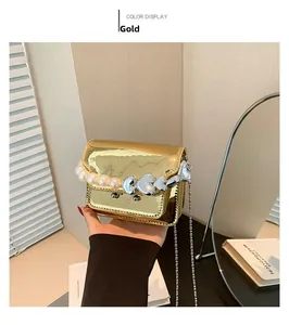 Detail of gold patent leather mini bag with pearl heart charm and silver chain