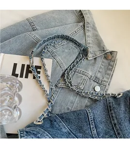 Détail de la bandoulière en denim et chaîne métallique d'un sac vintage avec boucles argentées