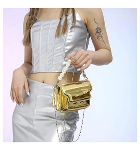 Detail of metallic gold mini square bag with large pearl handle and chain strap