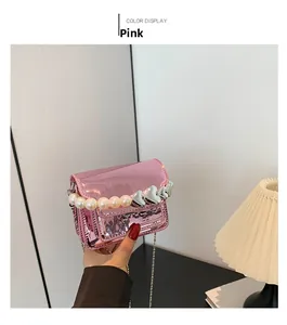 Detail of pink patent leather square bag featuring large pearls and silver heart charms