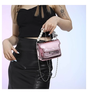 Close-up of metallic pink mini square bag featuring pearl handle and heart charm