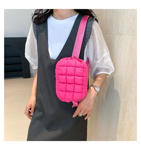 Detail of bright pink quilted crossbody bag with soft padded texture and woven strap
