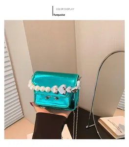 Close-up of green metallic mini bag featuring heart-pearl handle and silver chain