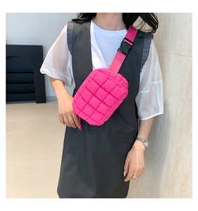 Close-up of rose red quilted crossbody bag with wide adjustable strap and buckle