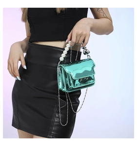 Detail of lime green patent leather mini bag with pearl handle and silver chain strap