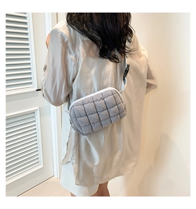 Close-up of a light grey quilted square pattern crossbody bag with adjustable strap