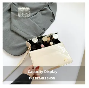 Vue intérieure d'un sac bandoulière en cuir verni beige montrant le rangement du maquillage