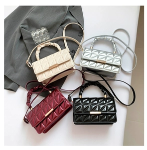 Vue de quatre sacs à main brillants en cuir verni matelassé en blanc, argent, rouge et noir