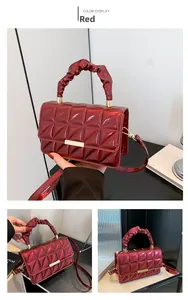 Détail du sac rouge matelassé en cuir verni avec boucle dorée et anse plissée