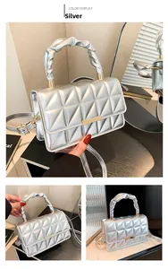Détail du sac argenté matelassé avec poignée plissée et boucle métallique décorative