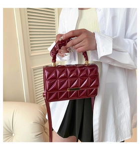 Détail du sac à main en cuir verni bordeaux avec motifs matelassés et anse froncée
