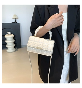 Détail du sac matelassé en cuir verni blanc avec poignée froncée et finitions métalliques dorées