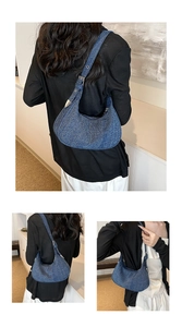 Detailed view of adjustable denim shoulder strap and metal hardware on crescent bag