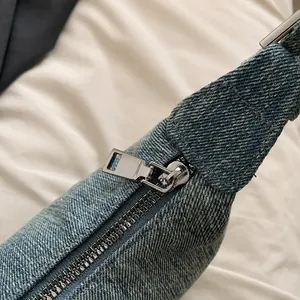 Close-up of high-quality silver metal zipper on light blue denim shoulder bag