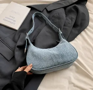 Detailed close-up of light blue denim crescent bag texture and adjustable silver buckle