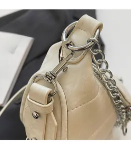 Macro detail of high-quality silver metal hooks and chain on a cream leather bag