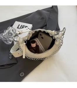 Detail view of white crescent bag interior with phone and perfume to show capacity