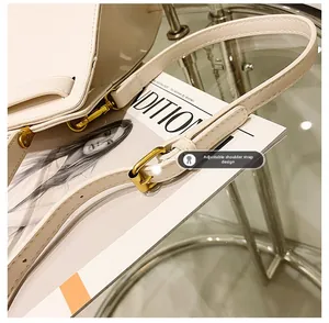 Détail de la bandoulière réglable avec boucles dorées sur un sac Kelly en cuir beige