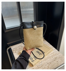 Detail of straw crossbody bag with black leather flap and large pearl closure