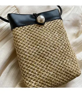 Detail of straw woven bucket bag with leather flap and elegant large pearl closure
