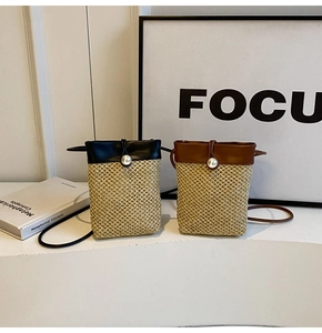 Detail view of mini straw woven crossbody bags with faux leather trim and pearl closure