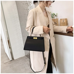 Sac à main trapèze en cuir noir moderne avec fermoir doré porté en bandoulière chic