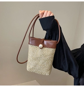 Detail of hollow straw phone bag with contrast leather trim and large pearl button