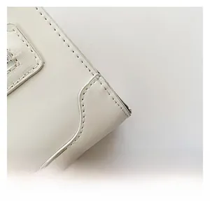 Détail macro de la texture du cuir blanc et des coutures précises sur le sac bandoulière