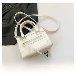 Détail d'un sac à bandoulière en cuir PU blanc avec pompon et bandoulière réglable