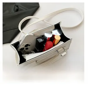 Détail de l'intérieur spacieux du sac à bandoulière en cuir blanc avec téléphone et rouge à lèvres