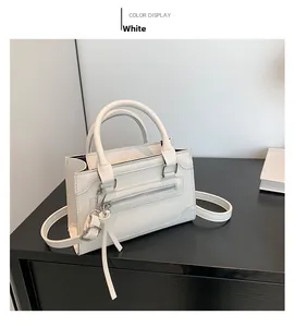 Vue détaillée d'un sac bandoulière blanc brillant avec fermetures éclair décoratives