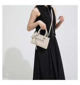 Détail du sac bandoulière crème avec ferrures argentées et texture en cuir grainé
