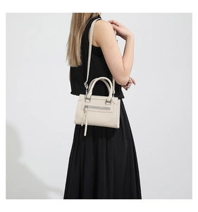 Détail d'un sac bandoulière beige avec fermeture éclair à franges et bandoulière amovible