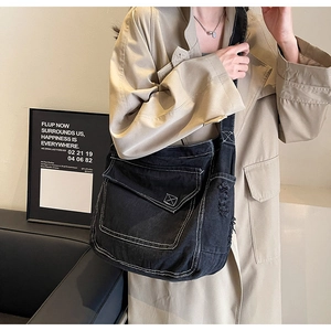 Dettaglio della borsa a tracolla in denim nero con cuciture bianche e dettagli consumati