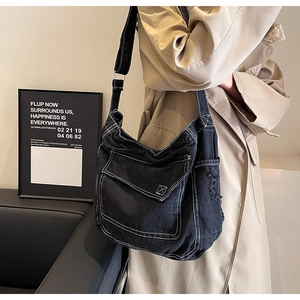 Dettaglio borsa hobo in denim nero con cuciture a contrasto e tasche sulla tracolla larga
