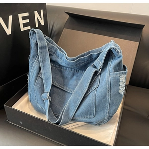 Dettaglio della borsa a tracolla in denim blu con bordo floreale sfrangiato e tracolla