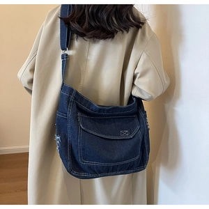 Dettaglio borsa hobo in denim blu con tasca frontale a patta e bordi sfrangiati vintage