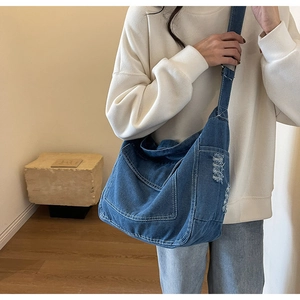 Dettaglio della borsa a tracolla in denim blu con cuciture a contrasto e bordi sfrangiati