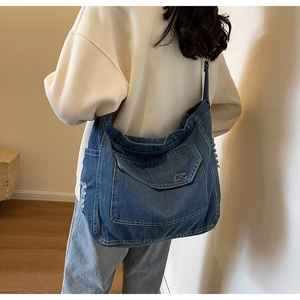 Dettaglio della borsa a tracolla in denim blu con lavaggio vintage e design multi-tasche