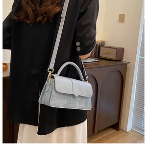 Detail van een lichtblauwe crossbodytas met steentextuur gedragen door een mooi model