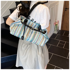 Detail of colorful zigzag weave texture and black shoulder straps on a straw baguette bag