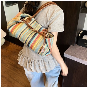Detail of colorful woven straw shoulder bag with brown leather straps and buckle