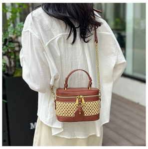 Outdoor lifestyle view of a woven vanity box bag with brown leather and gold chain strap