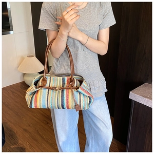 Detail of colorful striped straw shoulder bag featuring brown leather strap and buckle