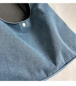Détail du tissu en denim bleu souple et boucle en métal argenté du sac à bandoulière