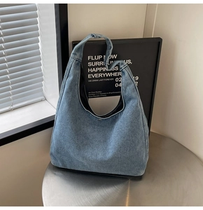Gros plan du sac bandoulière en jean bleu clair avec large sangle et bouton pression