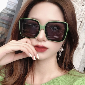 Close-up of oversized square sunglasses in avocado green with dark gray resin lenses
