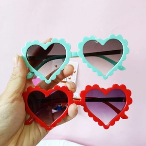 Lunettes de soleil cœur pour enfants en vert et rouge avec monture ondulée et verres foncés